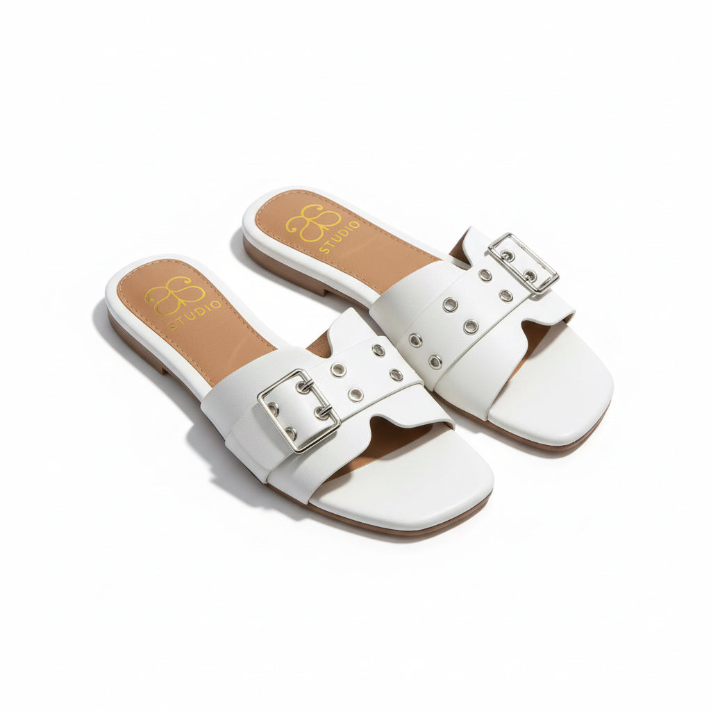Pair of white sandals with buckles on a wooden floor