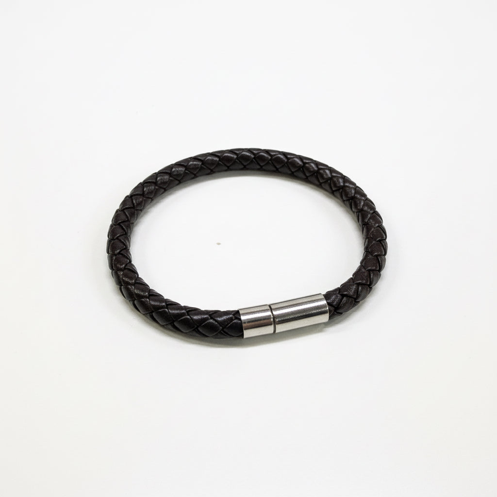 Black braided leather bracelet with a metal clasp on a light gray background