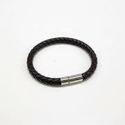 Black braided leather bracelet with a metal clasp on a light gray background