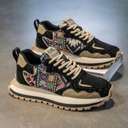 Black and beige sneakers with tribal pattern on a gray surface