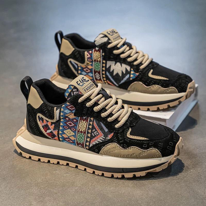 Black and beige sneakers with tribal pattern on a gray surface