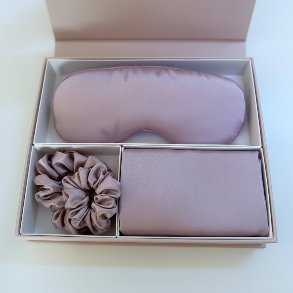 Set of pink eye mask, scrunchie, and pouch in a box on a white background