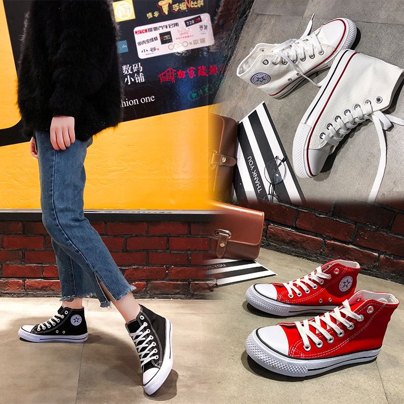 Person wearing black and red high-top sneakers with a brick wall and yellow surface in the background.