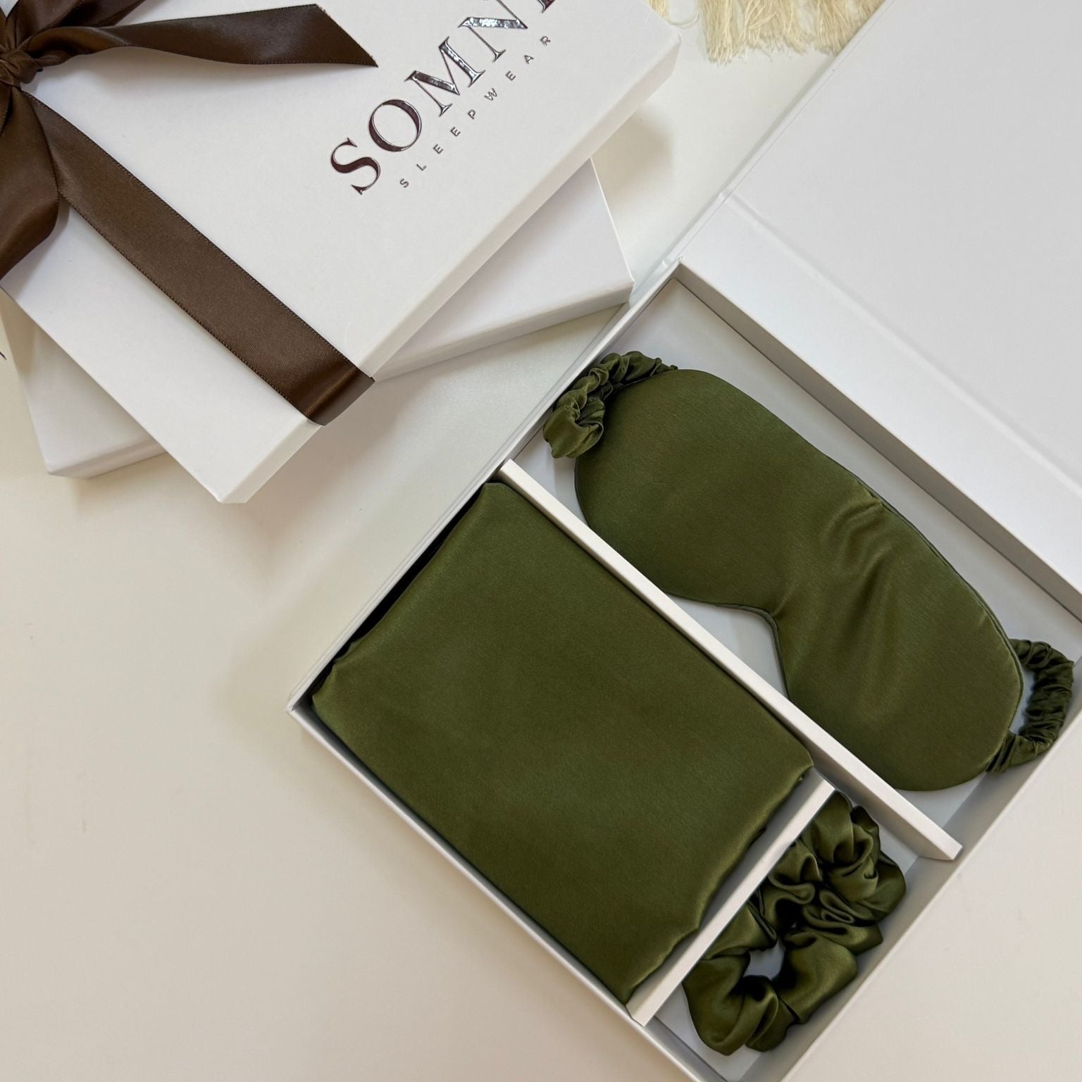 Sleep mask, earplugs, and green travel pillow in a white box with 'Somni' branding.