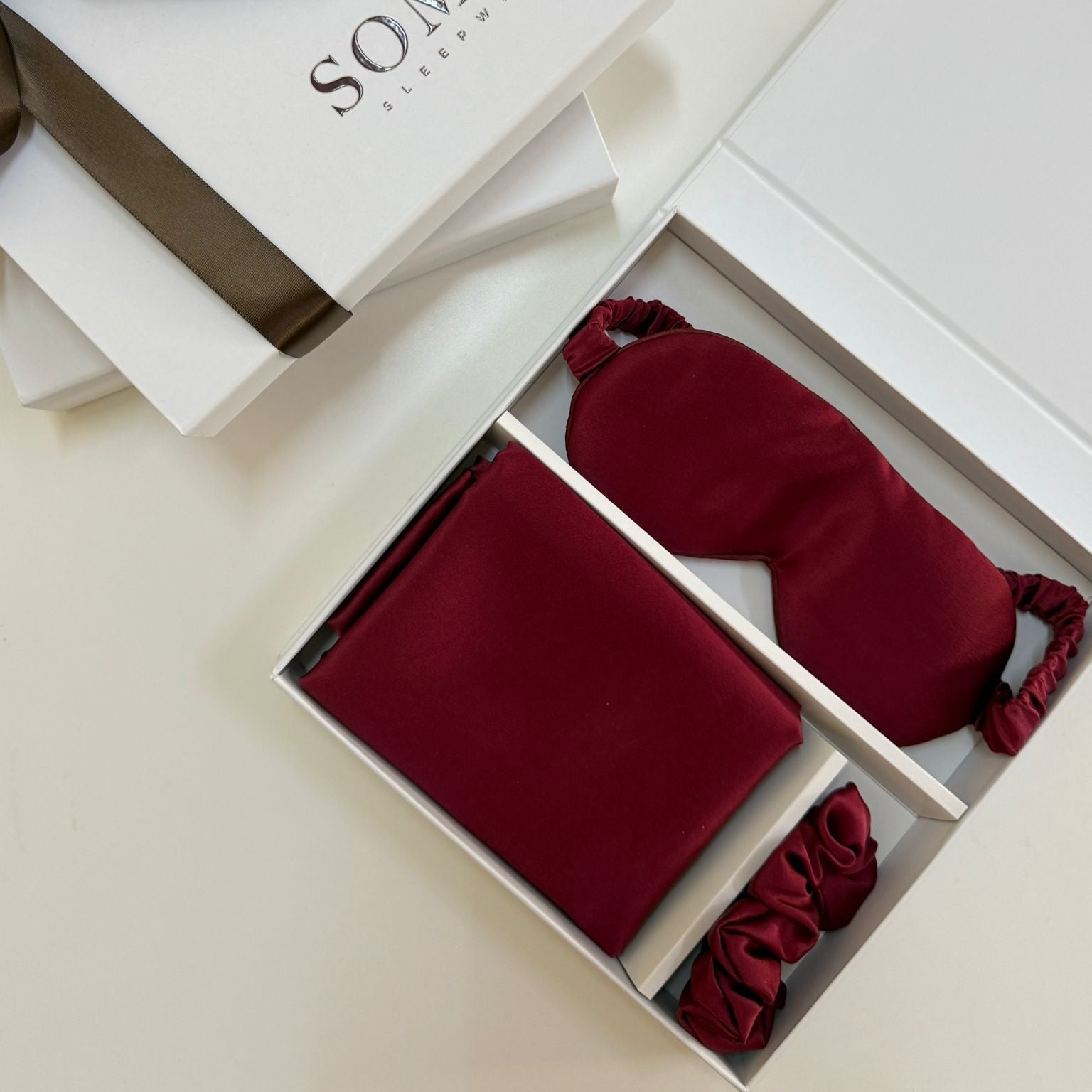 Red sleep mask and earplugs in a white box with 'SOMNI' branding.