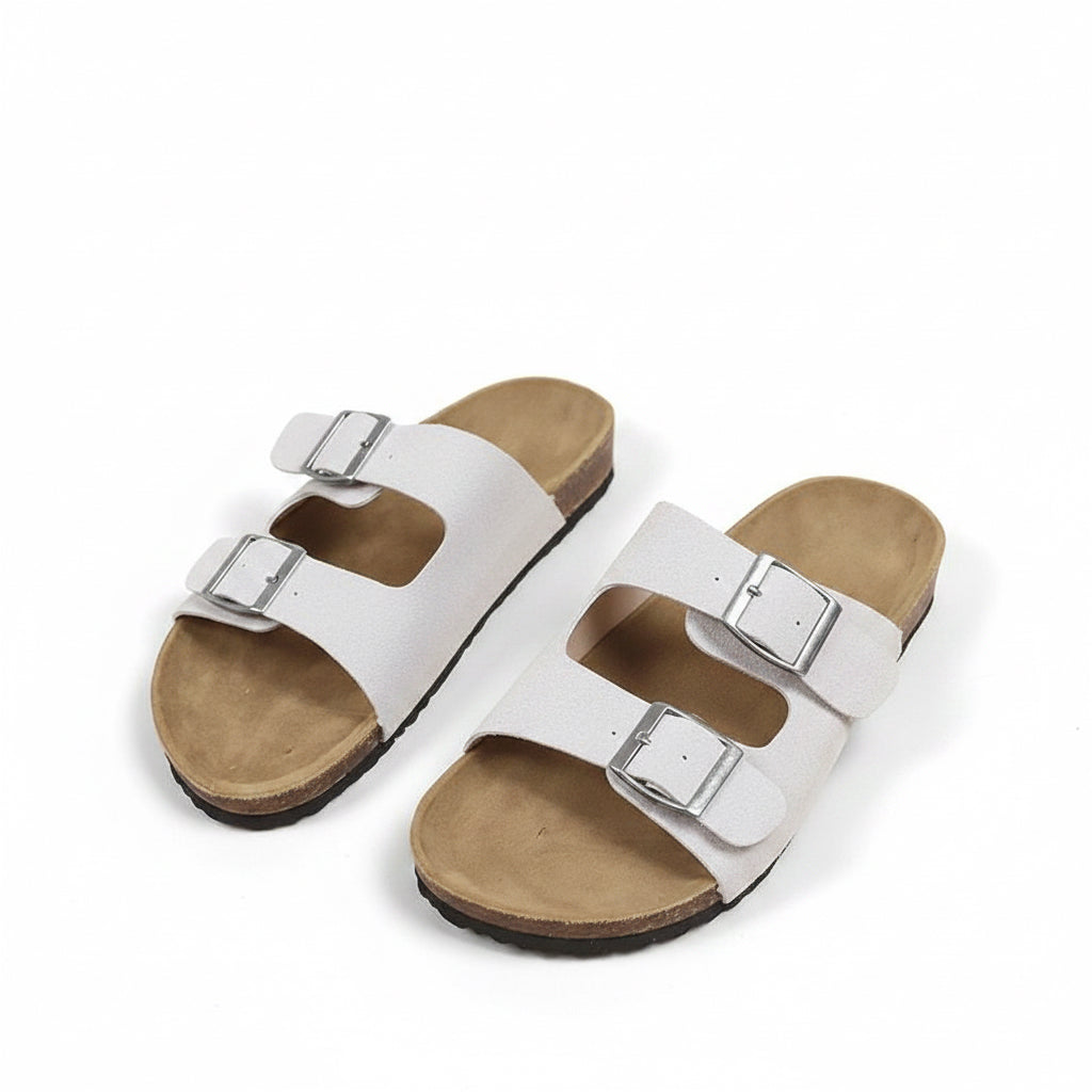White sandals with gold buckles on a beige background