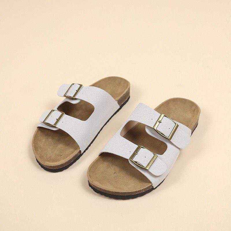 White sandals with gold buckles on a beige background