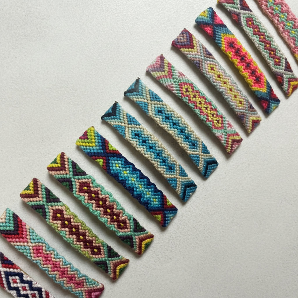 A collection of colorful woven wrist bands displayed in a plastic packaging.