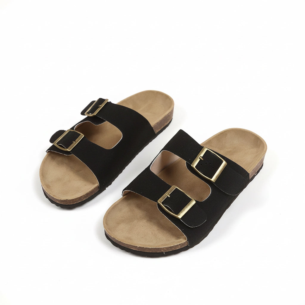 Pair of black sandals with gold buckles on a beige background
