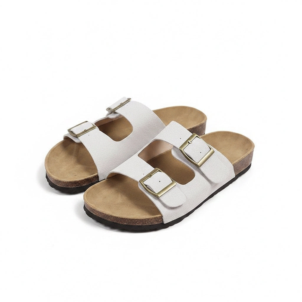 Pair of white sandals with brown soles on a beige background