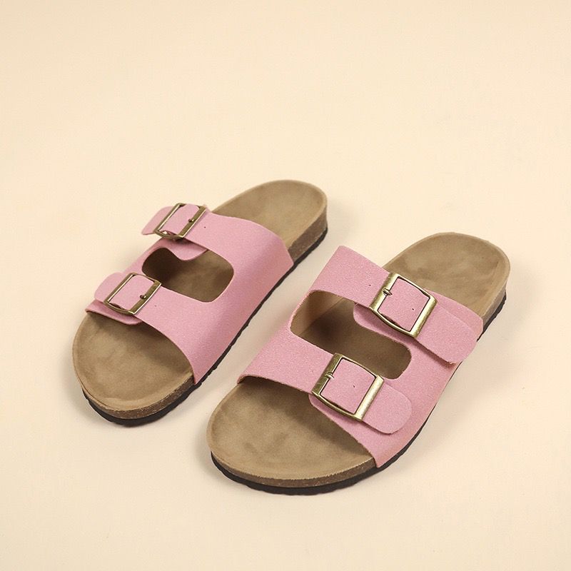 Pair of pink sandals with brown soles on a beige background