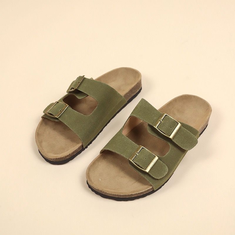 Pair of green sandals with brown soles on a beige background