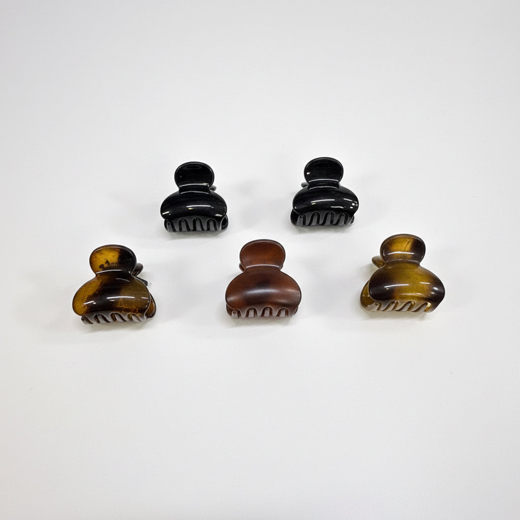 Set of six dark brown hair clips on a black card with a green border against a white background