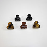 Set of six dark brown hair clips on a black card with a green border against a white background