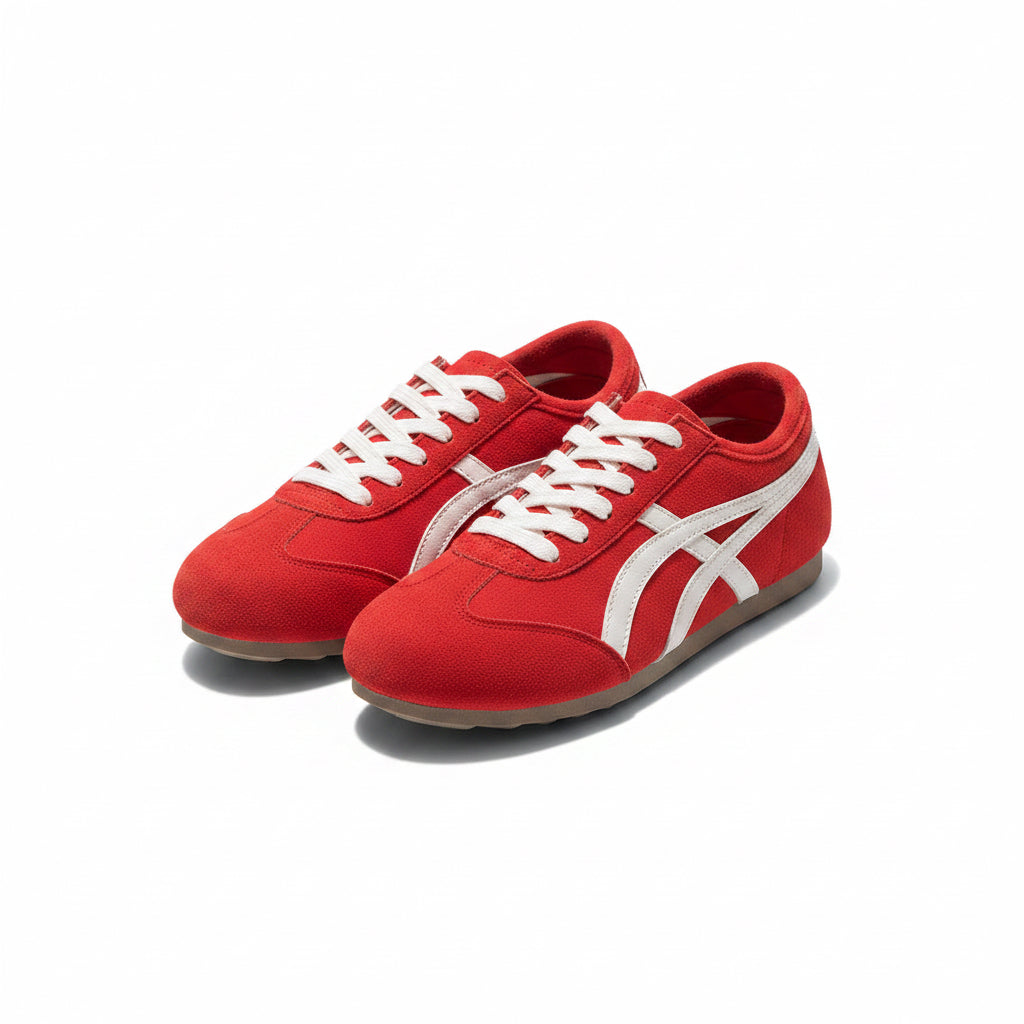 Red sneakers with white accents on a dark surface next to a red cap and beige bag.