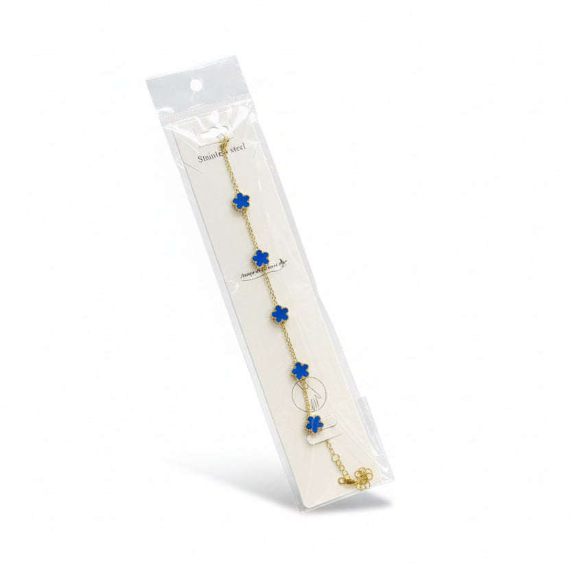 Gold bracelet with blue flowers in packaging on a white background