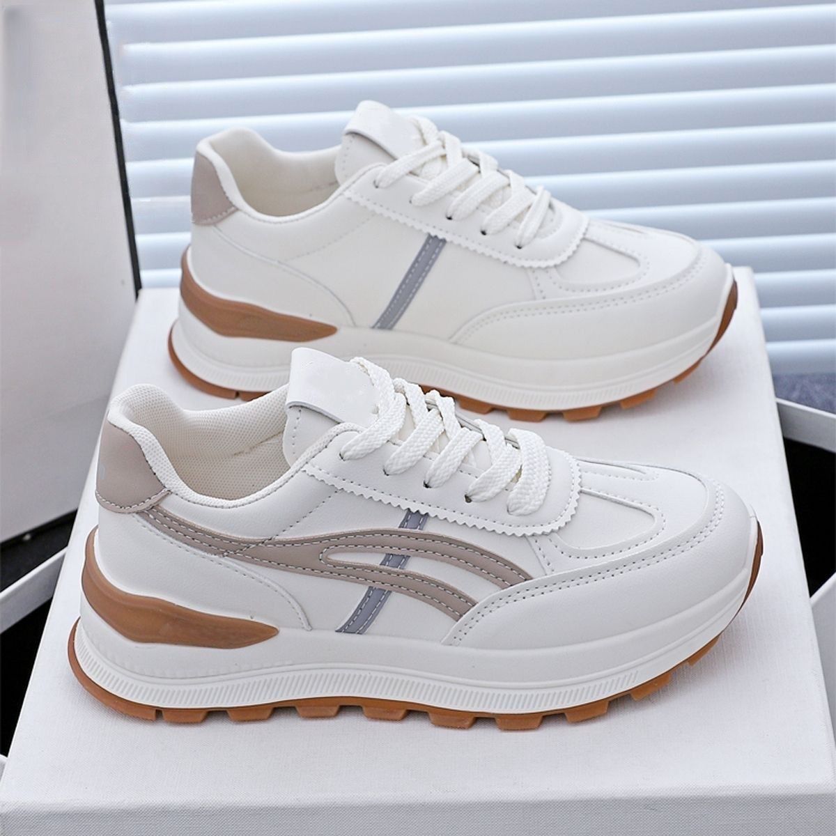 White sneakers with brown soles on a white surface