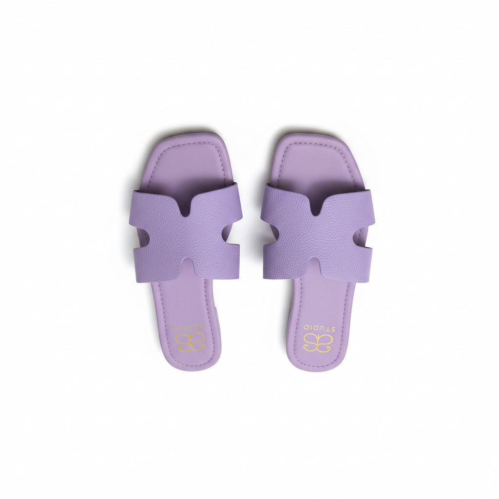 Pair of purple sandals with a brand tag on a wooden surface