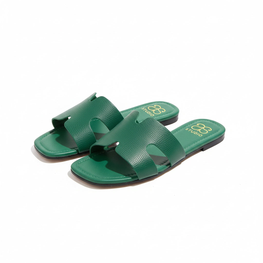 Pair of green sandals with a brand logo on a wooden floor.