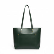 Green leather tote bag held by a hand on a light wooden surface