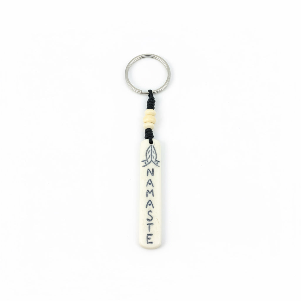 Vertical tan yak bone bar keychain with Namaste carving and orange bead.