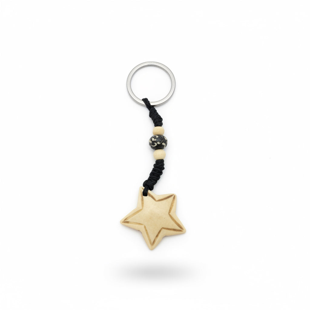 Star-shaped yak bone keychain with hand-carved border detail and black braided cord with beads.