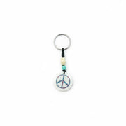 Circular yak bone keychain with a hand-carved peace sign and colorful inlay on a black braided cord.