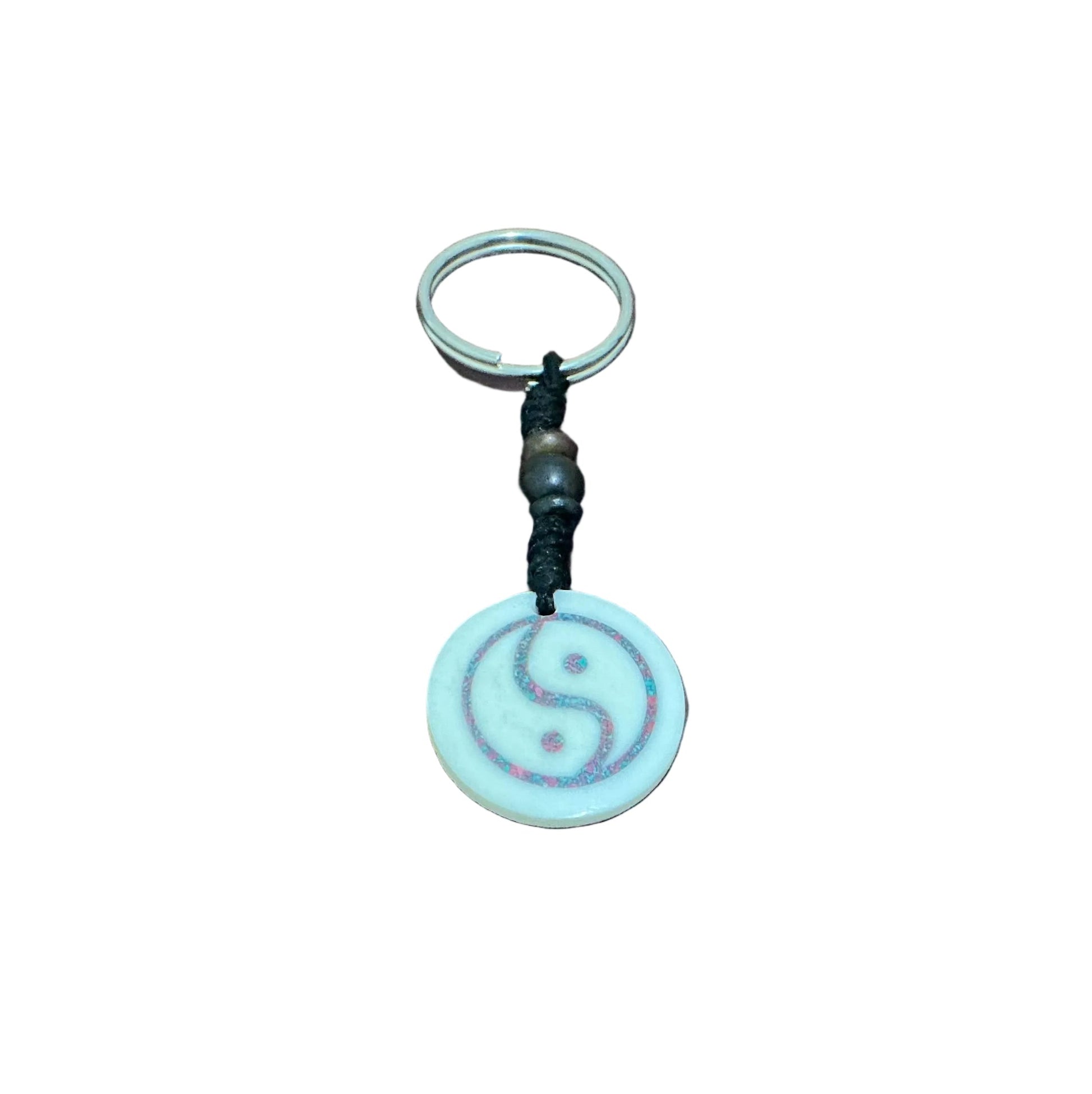 Circular white yak bone keychain with a hand-carved Yin Yang symbol and colorful red and blue inlay.