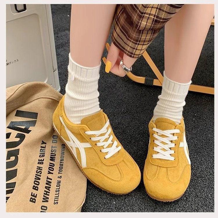 Yellow sneakers with white laces worn by a person sitting on a chair.