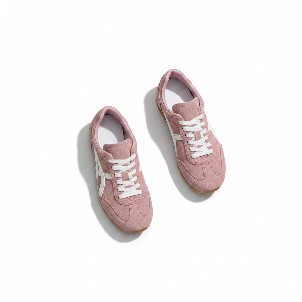 Pink sneakers with white accents worn by a person, with a beige bag and plaid fabric in the background.