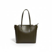 Brown leather handbag on a wooden surface with a white wall background