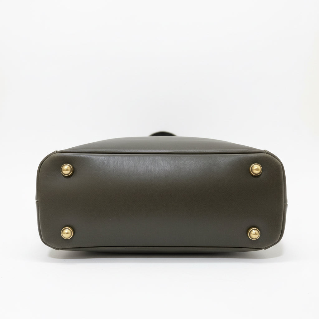 Brown leather bag with gold studs on a wooden surface