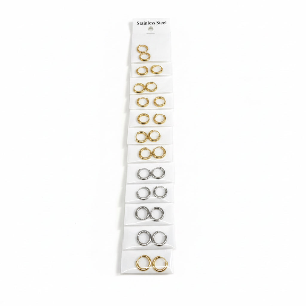 Set of gold earrings on a clear card against a white background