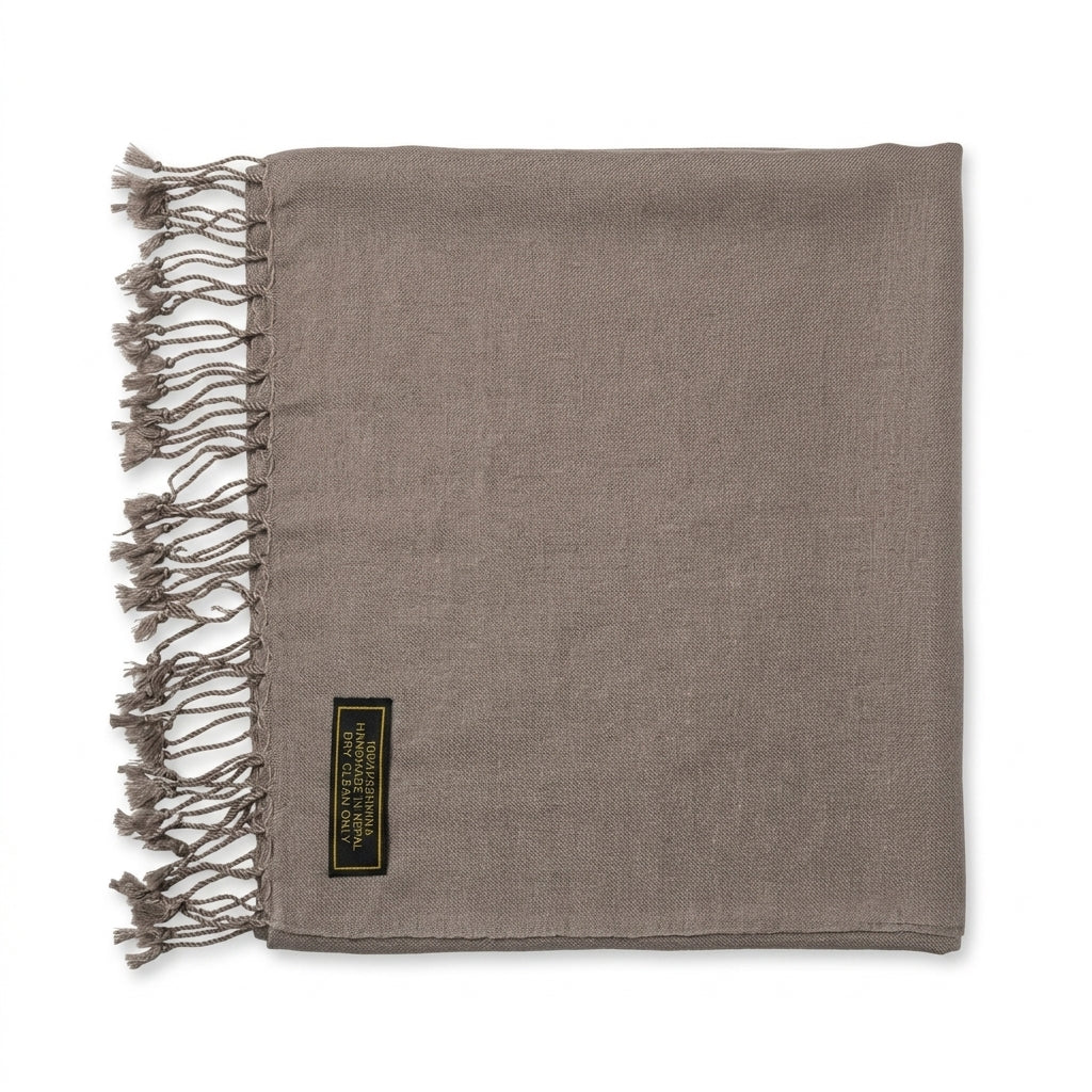 A taupe brown woven scarf with fringed edges and a small black brand label, laid flat on a white background.