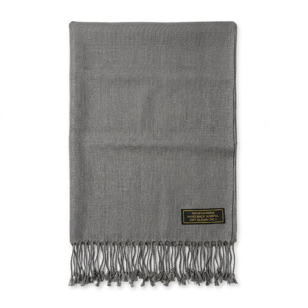 A folded gray woven scarf with fringed ends and a small black brand patch near the lower right corner, shown on a plain white background.