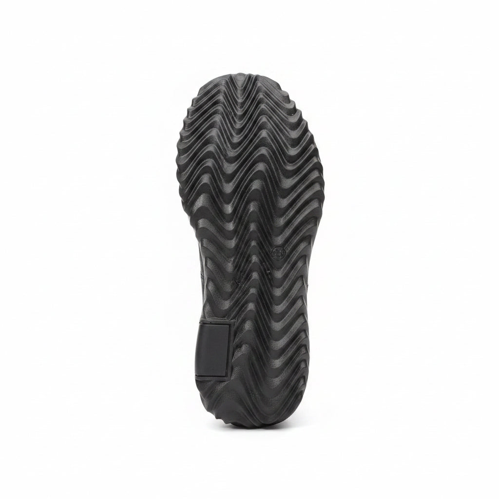 Close-up of a black boot sole with a textured pattern, likely on a workbench.