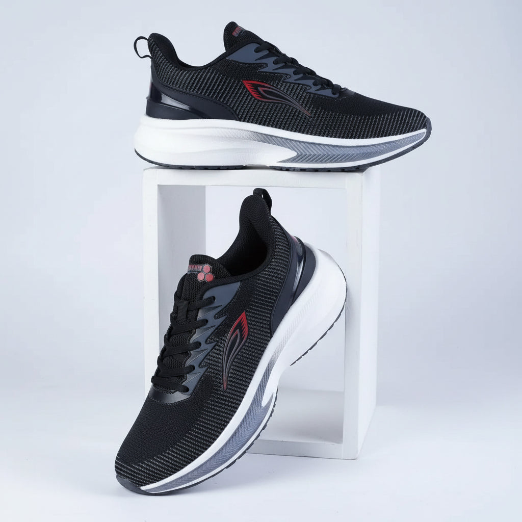 Black running shoes with dark grey textured lines, subtle red accents, a dark heel counter, and a thick white and grey cushioned sole.
