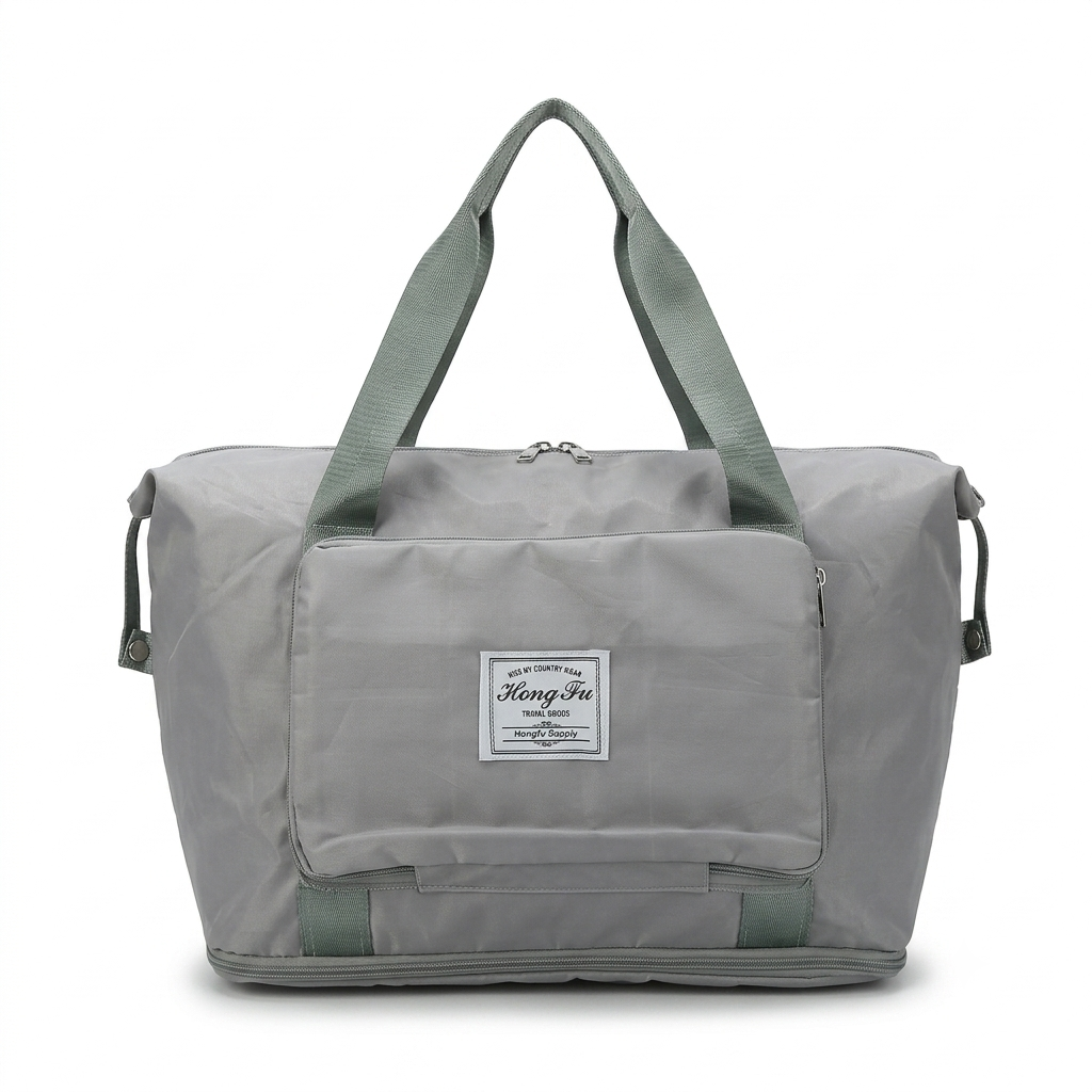 A light gray foldable duffel bag with sage green handles and trim, featuring a white rectangular brand patch on the front pocket. The bag is photographed against a clean white background.