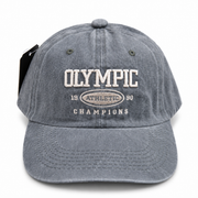 Front view of a vintage grey washed baseball cap with embroidered Olympic Athletic logo.