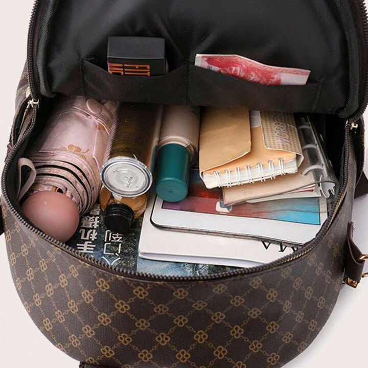 Open brown patterned bag with various items including a notebook and a can.