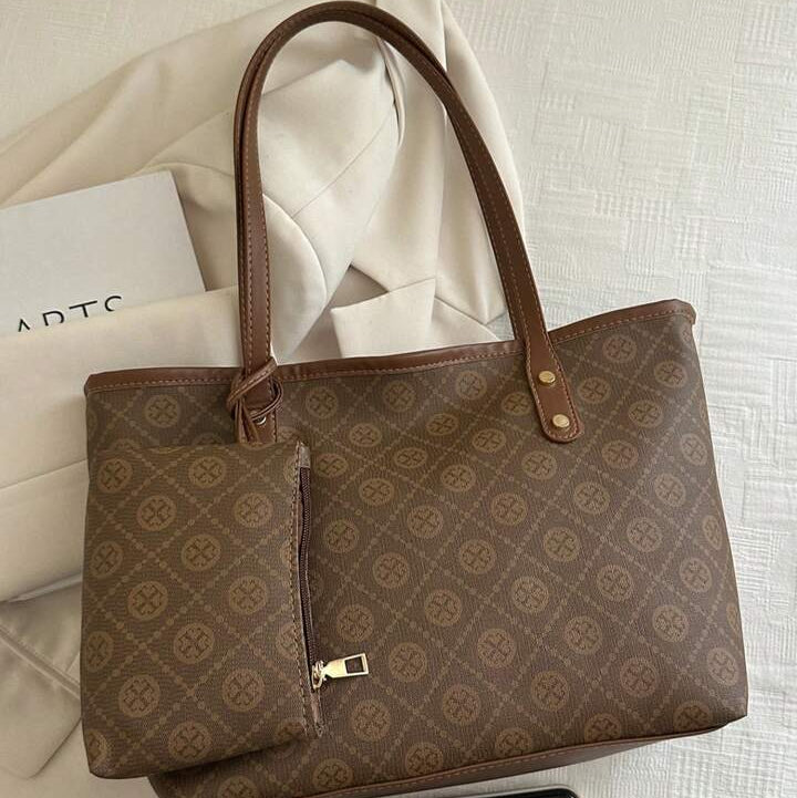 Brown patterned tote bag on a light fabric background with a phone and card.