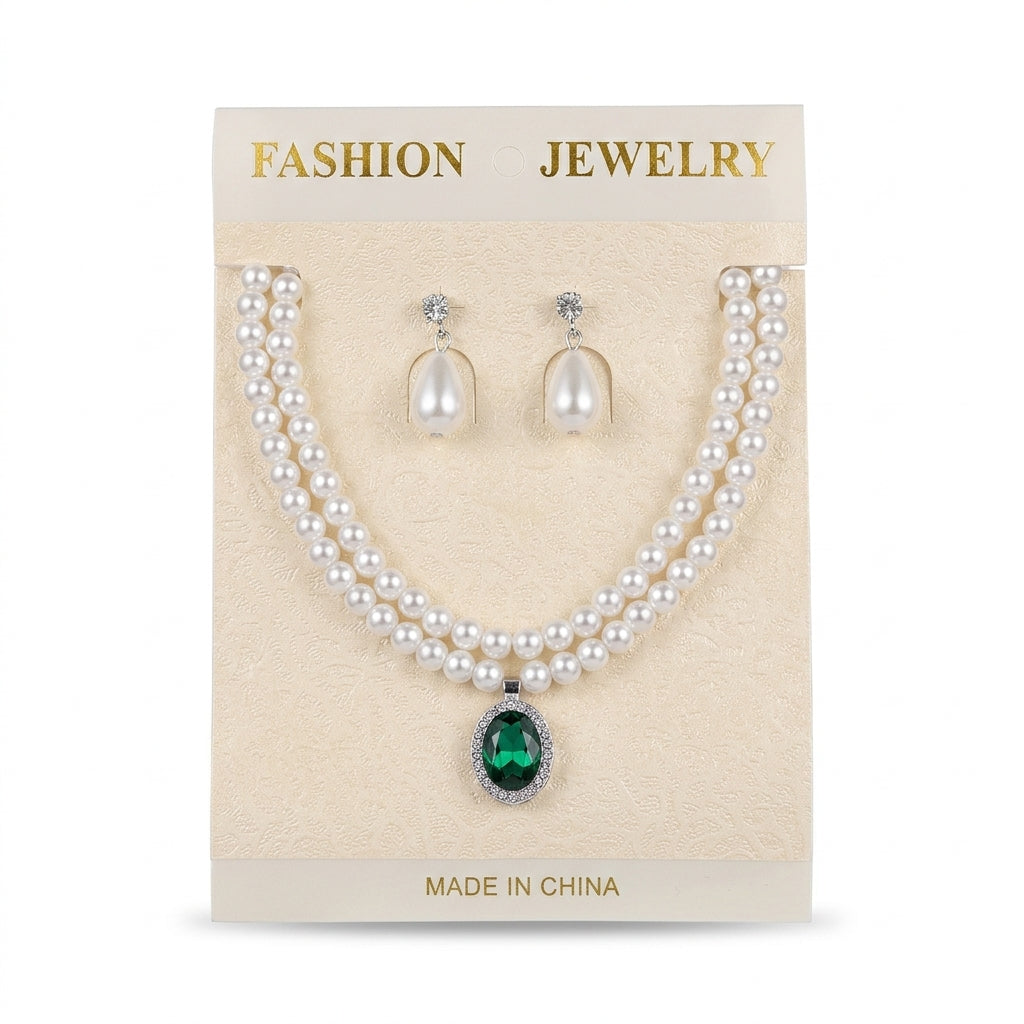 Women's double strand faux pearl necklace featuring an oval green gemstone pendant with matching pearl drop earrings on display card.