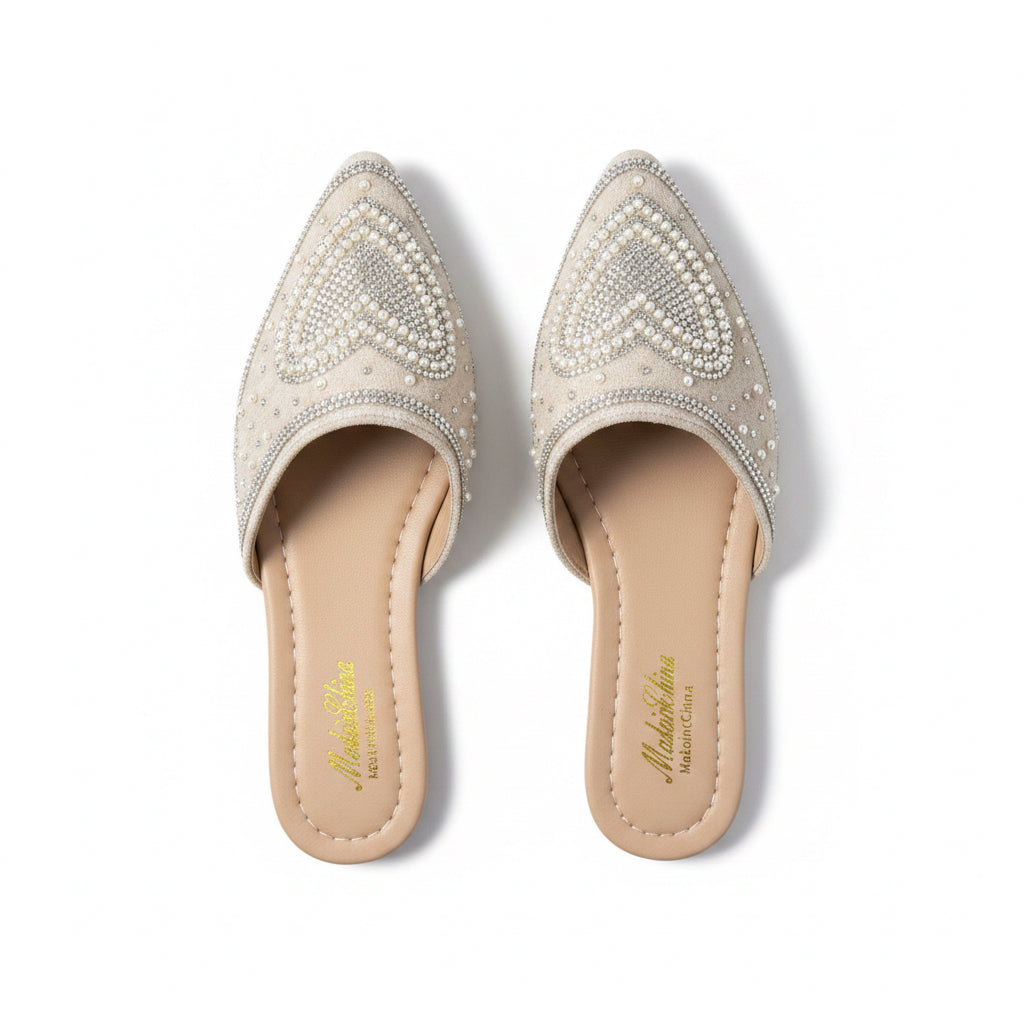 Womens beige pointed toe flat mules featuring decorative faux pearls and rhinestone heart designs