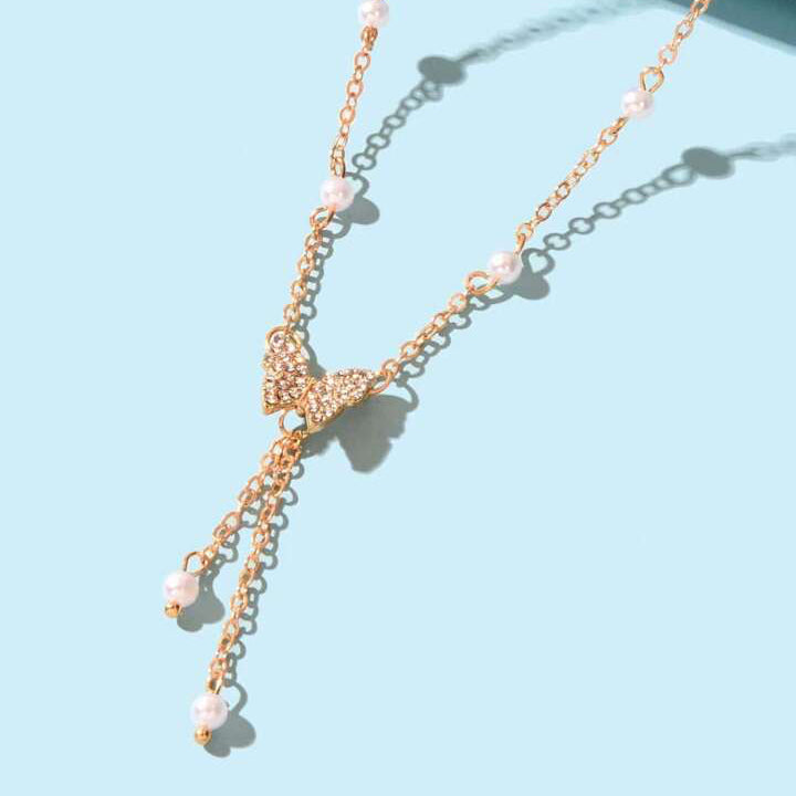 Womens gold choker necklace featuring a central butterfly charm and small white pearl details