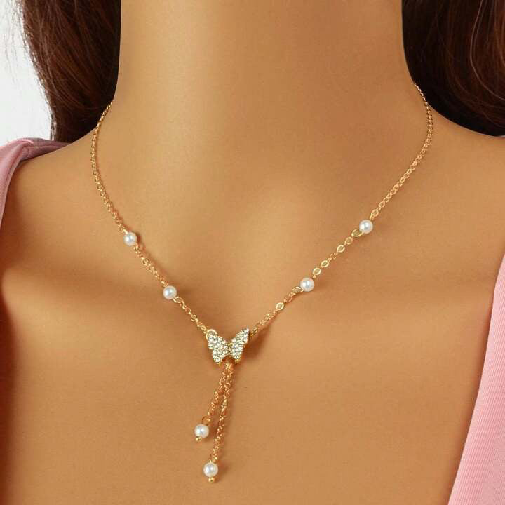 Womens gold choker necklace featuring a central butterfly charm and small white pearl details