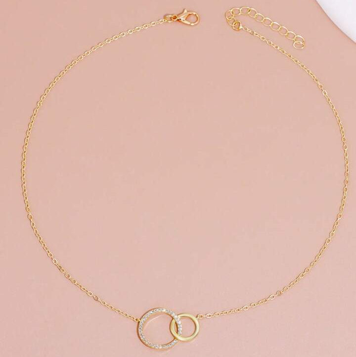 Gold necklace with interlocking rings on a pink background