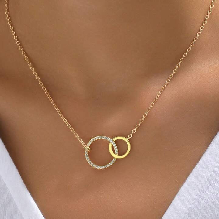 Gold necklace with interlocking rings on a person wearing a white top