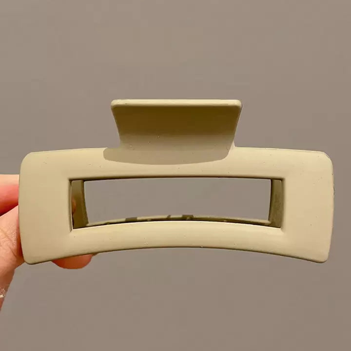 Beige hair clip held against a plain background