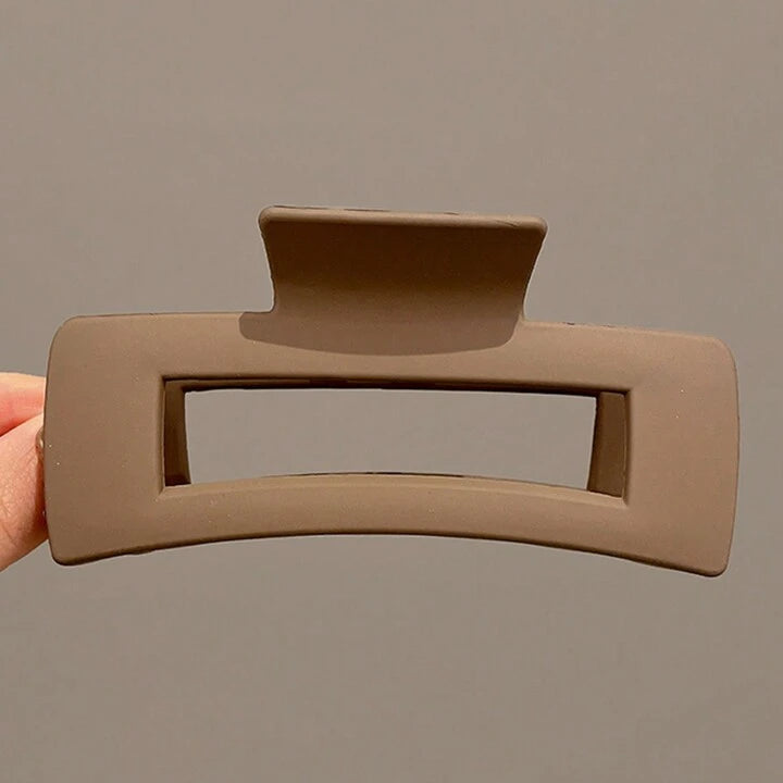 Brown hair clip held against a gray background