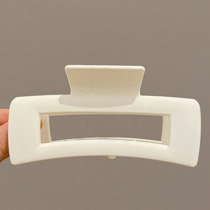White hair clip held against a brown background